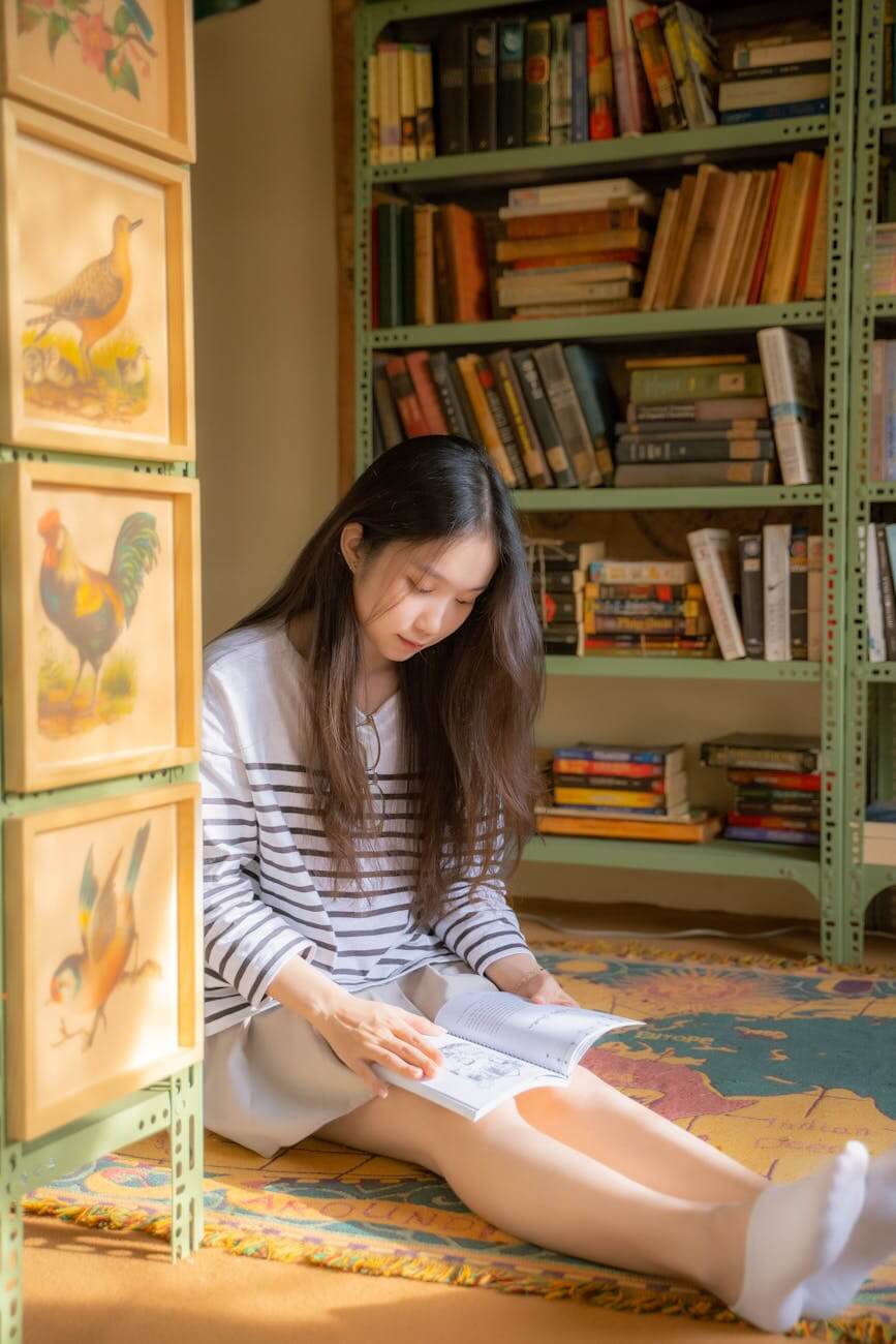 a teenage girl reading a book. CurioBuddy promotes creativity through reading and artistic imagination like poster making contests.